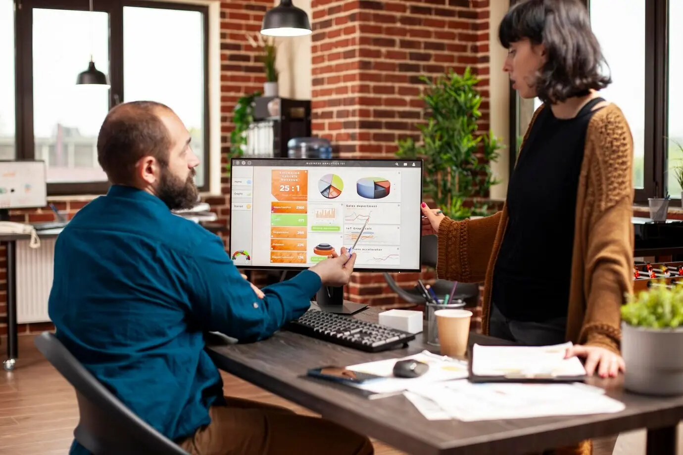 В офисе женщина слушает бизнесмена.